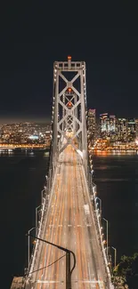 Nighttime view of a lit bridge with a city skyline.
