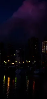 Dark cityscape at night with colorful reflections on water.