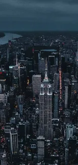 Aerial view of a city skyline illuminated at night with skyscrapers and a dark blue sky.