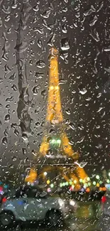 Eiffel Tower shines through rain-soaked window at night.