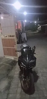 Sleek black motorcycle on a dimly lit street at night.