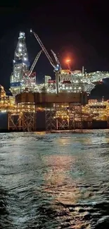 Illuminated offshore oil rig at night over dark ocean.