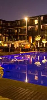 Nighttime view of illuminated hotel pool with warm lighting.