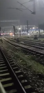 Night view of railway tracks with lights and station.