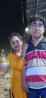 Couple standing on a nighttime street.