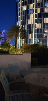 Night city view with glass building and palm trees.