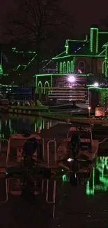 Night view of waterfront with green glowing reflections on the water and buildings.