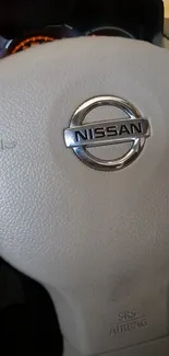 Nissan steering wheel close-up with logo emblem on leather background.