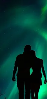 Silhouetted couple under the vivid Northern Lights sky.