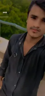 Portrait of a young man in an urban outdoor setting, wearing a dark shirt.