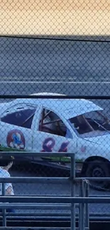 Vintage race car on track with nostalgic appeal, behind fence.