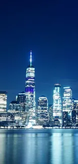 New York City skyline with blue night lights reflecting in water.