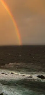 Vibrant rainbow stretching over a tranquil ocean at sunset.