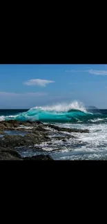 Dynamic ocean waves crash against rocky shore under a clear blue sky.