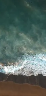 Aerial view of ocean waves meeting sandy beach, capturing nature's beauty.