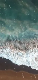 Aerial view of turquoise ocean waves crashing onto a sandy beach.