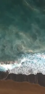 Aerial view of ocean waves meeting a sandy beach with deep teal waters.