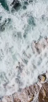 Aerial view of ocean waves crashing onto rocky shore with vibrant blue hues.