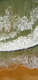 Aerial view of ocean waves meeting sandy beach.