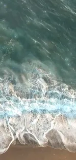 Aerial view of ocean waves on a sandy beach, captured as a mobile wallpaper.