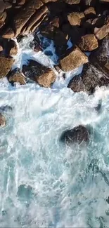 Aerial view of ocean waves crashing against rocks on a serene coastal shore.