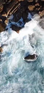 Aerial view of ocean waves crashing against rocks on the shore.