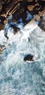 Aerial view of ocean waves crashing against rocks on a sunny day.