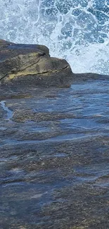 Ocean waves crashing on rocky shore on mobile wallpaper.