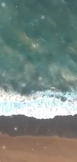 Aerial view of ocean waves meeting sandy beach with blue-green water.