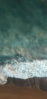 Aerial view of ocean waves gently washing onto a sandy beach.