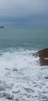 Moody ocean waves crashing against rocky shore.