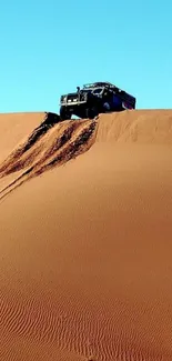 Off-road vehicle atop sand dunes under a clear blue sky.