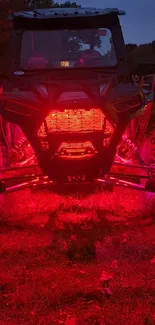 Off-road vehicle glowing red lights in a night scene on a grassy terrain.