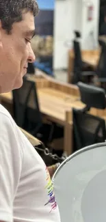 Man playing a drum in a modern office setting.