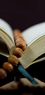 Open book with wooden prayer beads resting on pages.