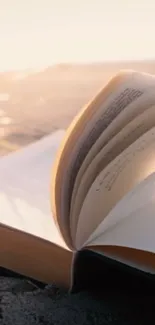 Open book on a sandy beach at sunset, capturing a serene moment.