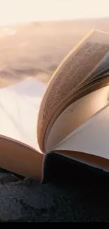 Open book resting on sandy beach at sunset, perfect for a serene background.