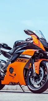 Orange sports bike on road under clear sky.