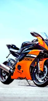 Vibrant orange sports motorcycle under clear blue sky wallpaper.