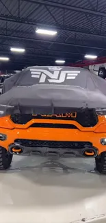 Striking orange truck under cover in garage.