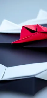 Red and white origami on a black surface, creating a striking abstract design.