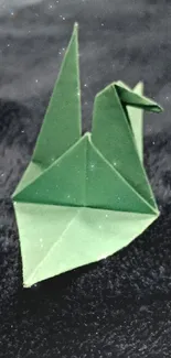 Green origami crane on a dark blue textured background.