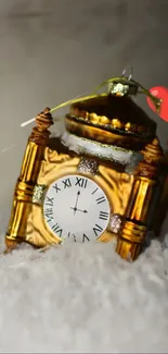 Golden clock ornament with snow and heart accent on a white background.