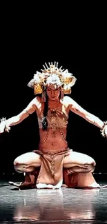 Intricate dance performer in ornate costume on dimly lit stage.