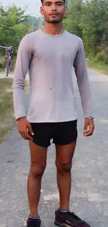 Young man in athletic gear standing outdoors on a scenic path.