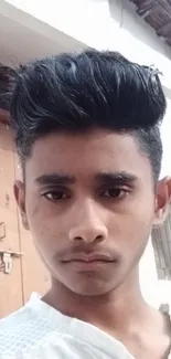 Portrait of a young person in a white shirt, outside a building.