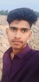 Young man outdoor portrait with stone backdrop.