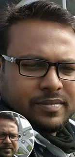 Man in glasses by a large metallic wheel outdoor.