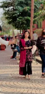 Urban street scene with people walking along a tree-lined path.