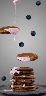 Stack of pancakes with blueberries and pink cream on a grey background.